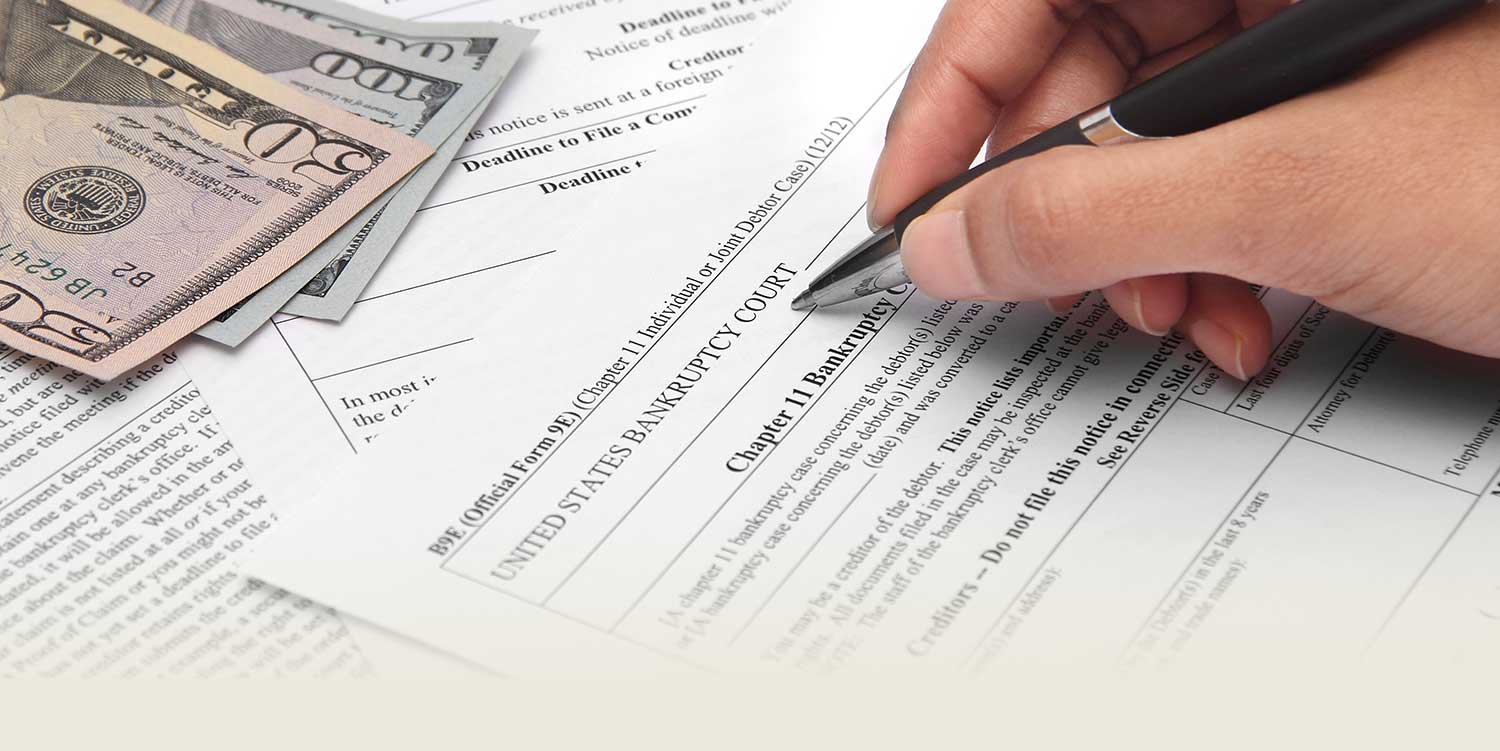 Documents for bankruptcy on a table with cash